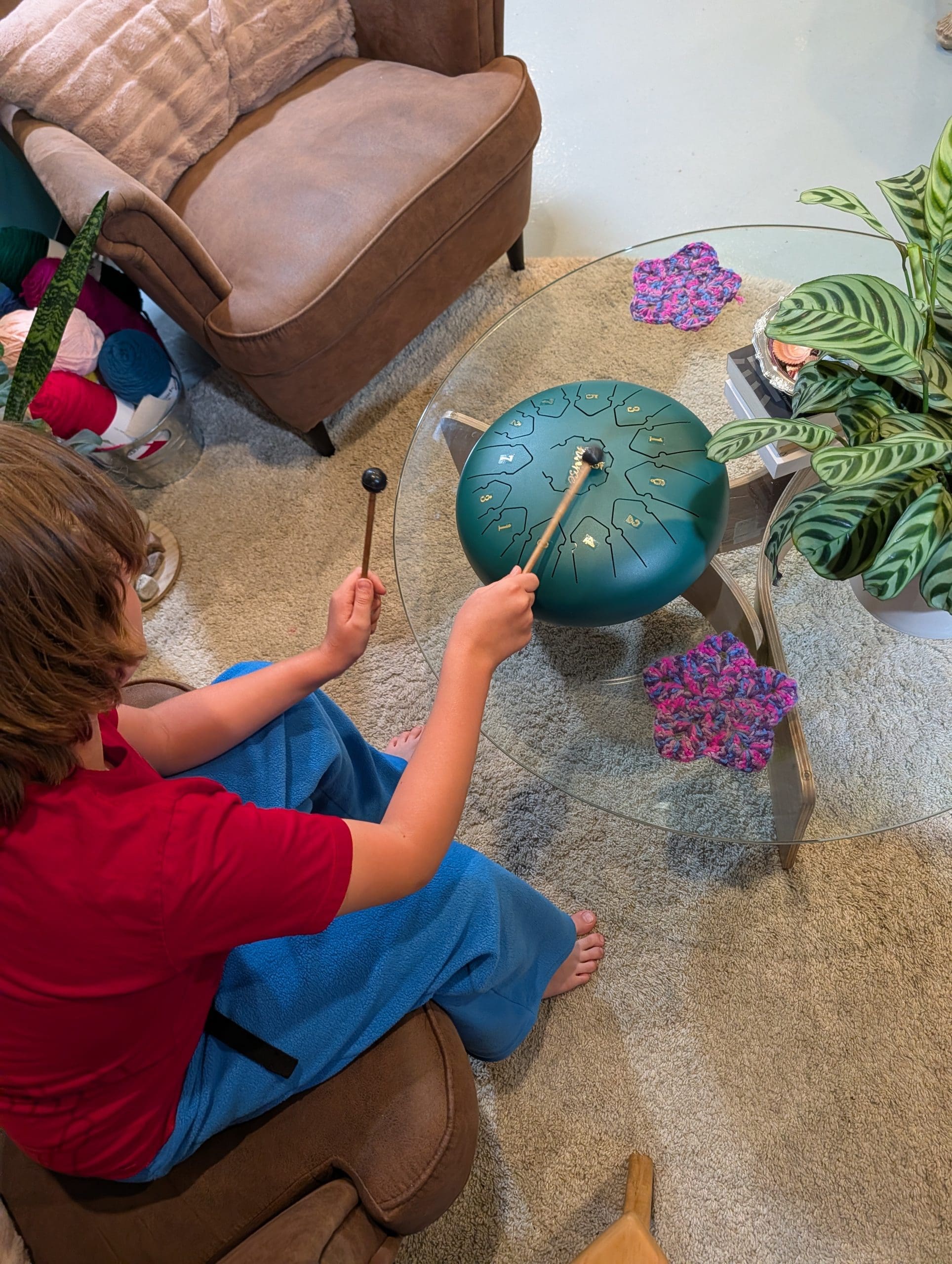 child creating music on a rain drum. child-centred art therapy